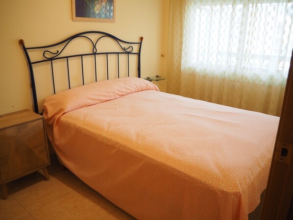 Una cama individual con cabecera, una mesita de noche y una mesilla.