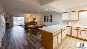 Amplia sala de estar con una mesa de comedor, un sofá y una cocina con armarios de madera y salpicadero de azulejos.