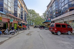 A street with buildings, parked motorcycles, and a red van. - Spot On 91500 Suci Homestay Syariah (Batam)