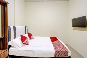 A hotel room with a bed, a television mounted on the wall, and a wooden wardrobe. - Spot On 91500 Suci Homestay Syariah (Batam)