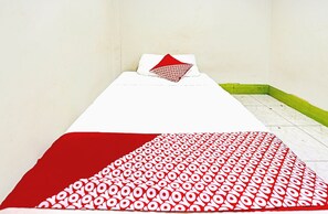 A single bed with a white mattress and a red and white patterned blanket.