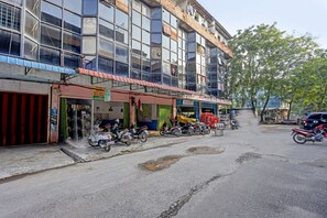 A street with parked motorcycles and a building with multiple shops.