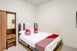 A neatly arranged hotel room with a bed, a wooden wardrobe, and a mirror. - Spot On 91500 Suci Homestay Syariah (Batam)