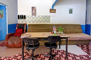 A room with a sofa, two chairs, a table, and a patterned rug.