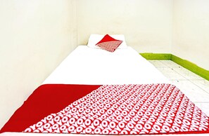 A single bed with a white and red patterned bedspread, a white pillow, and a red pillow with a circular pattern. - Spot On 91500 Suci Homestay Syariah (Batam)