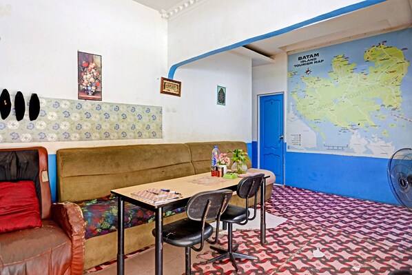 A room with a sofa, a table with chairs, a map on the wall, and a patterned floor.