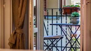 Ein Balkon mit Tisch und Stühlen, Blumentöpfen und Blick auf die Straße.