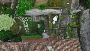 Eine Vogelperspektive zeigt einen Innenhof mit Steintreppen, einer kleinen Gartenanlage und einem Ziegeldach im Vordergrund.