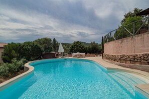 Une piscine avec un mur en pierre et une table entourée de chaises.