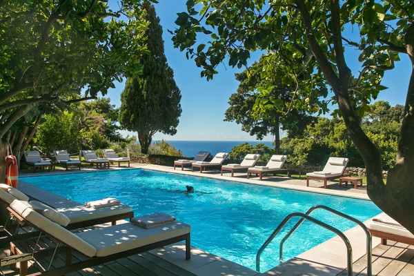 Una piscina al aire libre, sombrillas, sillones reclinables de piscina