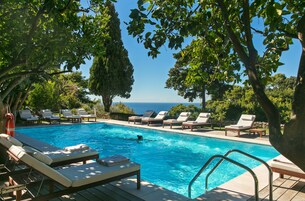 Una piscina al aire libre, sombrillas, sillones reclinables de piscina
