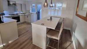 Uma cozinha moderna com uma ilha central, iluminação pendente e vista para o exterior através de uma janela.