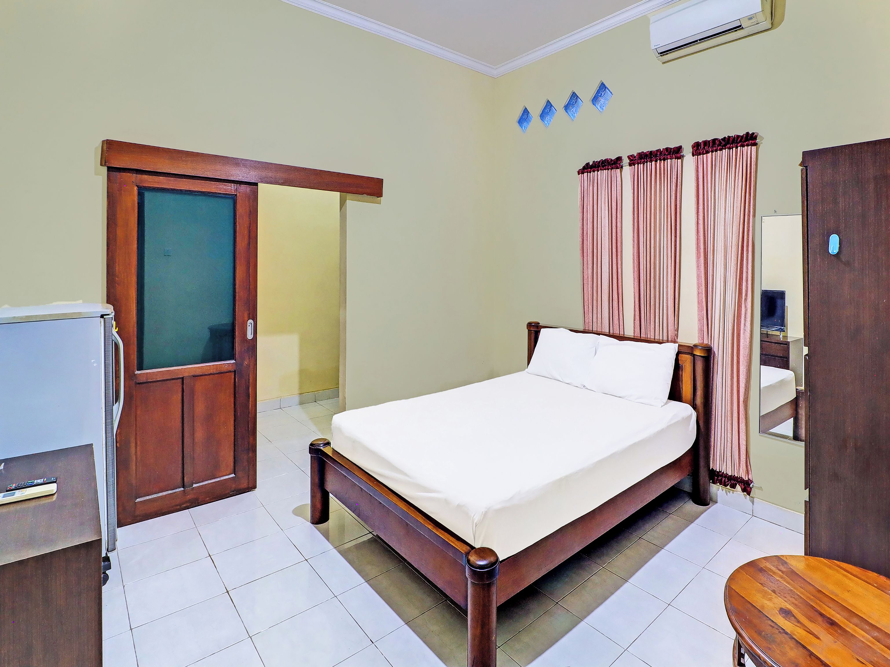 Quarto de hotel com cama, escrivaninha, guarda-roupa e espelho.