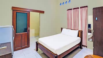 Quarto de hotel com cama, escrivaninha, guarda-roupa e espelho.
