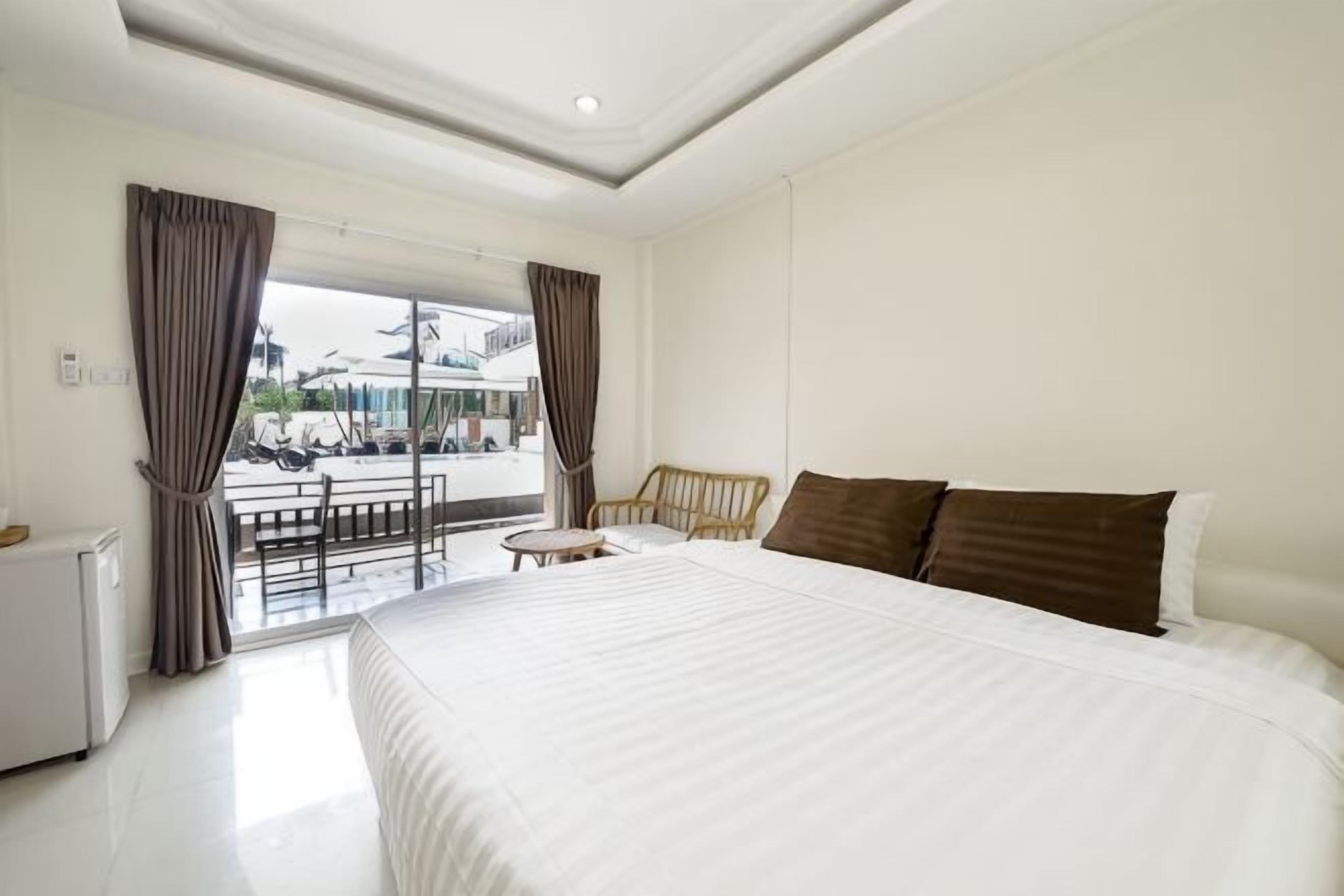 Een hotelkamer met een groot bed, een tafeltje, een stoel en uitzicht op de straat.