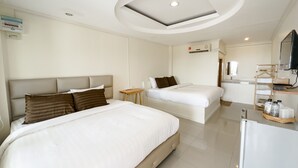 A hotel room with two beds, a small table, a TV, and a bathroom area.