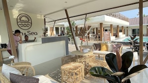 A reception area with wicker furniture, a reception desk, and a sign that reads "Sea & Sea".