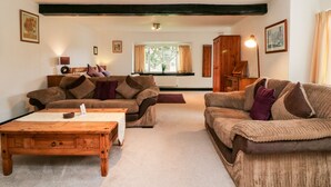 A cozy living room with two brown sofas, a wooden coffee table, and a wooden cabinet. - Priory House Cottage (Barnstaple)