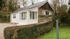 A stone house with a white exterior, a sloped roof, and a small porch. - Priory House Cottage (Barnstaple)