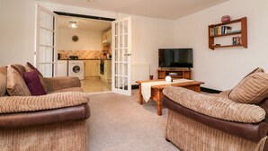 A living room with two sofas, a coffee table, a television, and a bookshelf. - Priory House Cottage (Barnstaple)