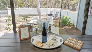 A table with a bottle of wine, cheese, crackers, and a wooden tray with starfish decorations. - 3880 Casa Azul - Near Hiking Trails, Golf & Town (Pebble Beach)