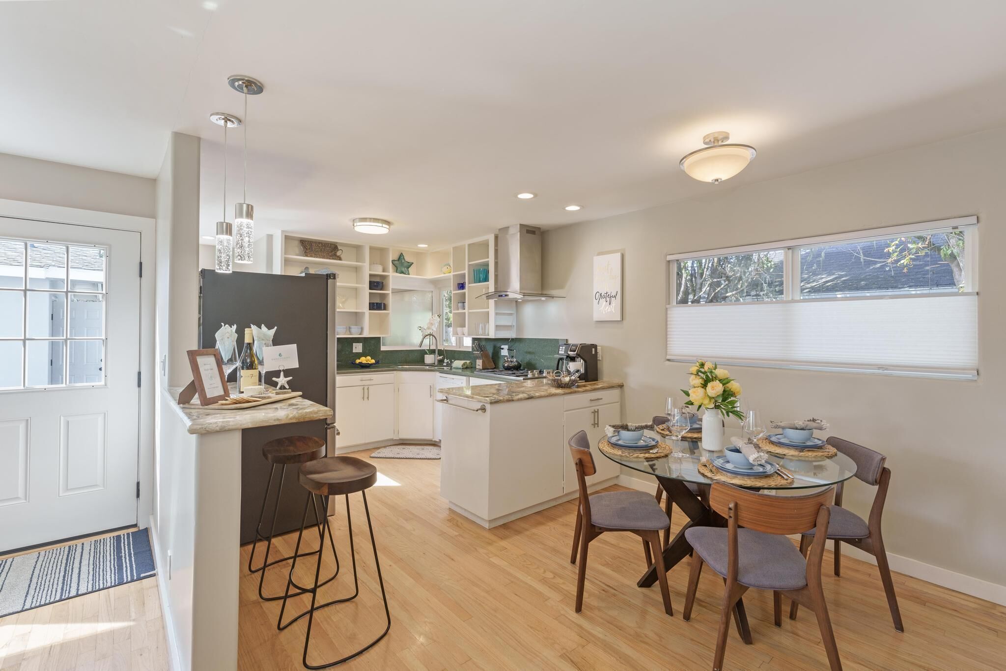 Een moderne keuken met een centraal eiland, barkrukken en een eettafel voor zes personen.