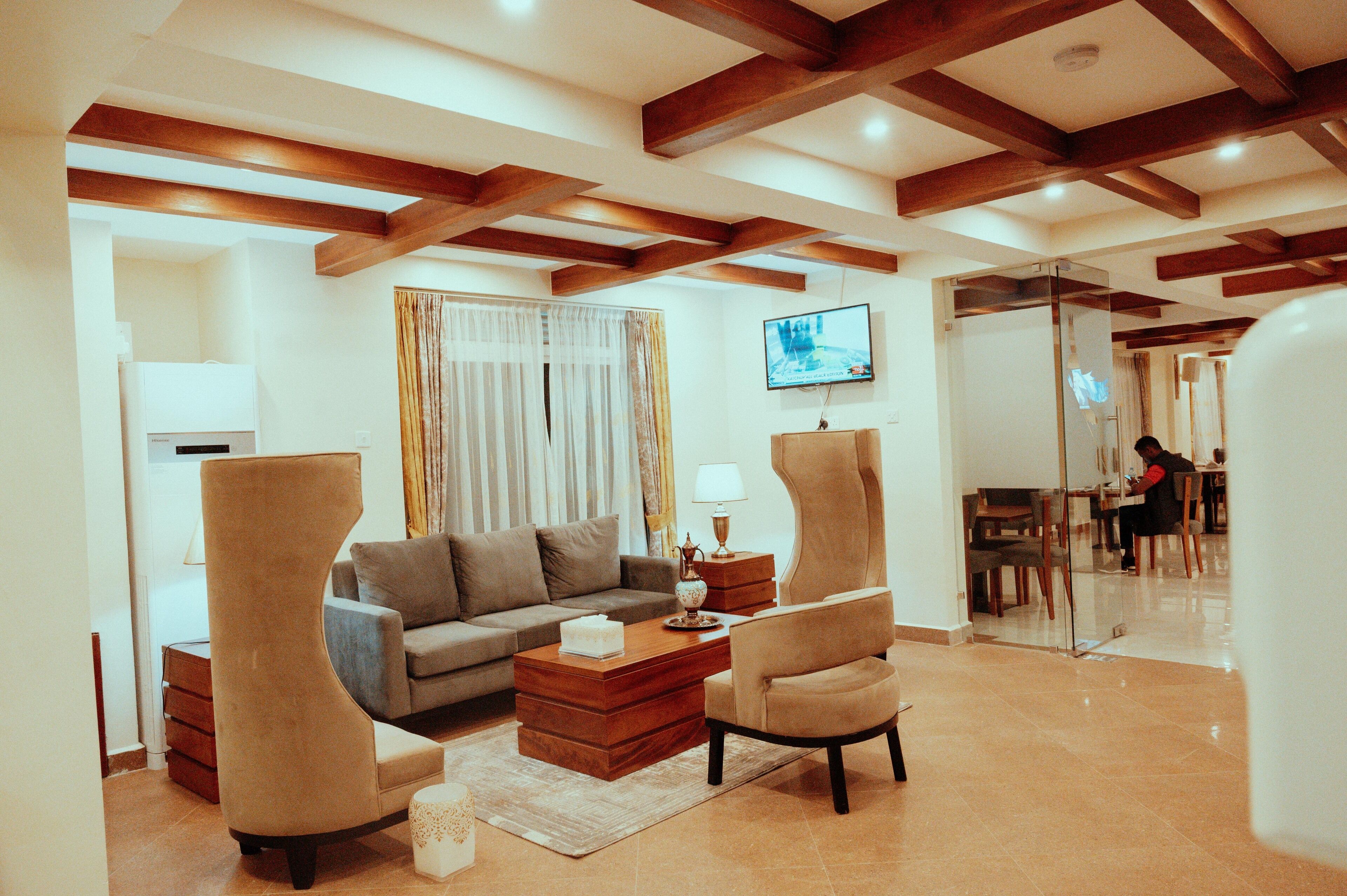 A modern living room with a sofa, two armchairs, a coffee table, and a television.