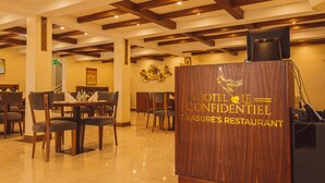 Un área de recepción con paneles de madera, una mesa de recepción y varias mesas de comedor con sillas.