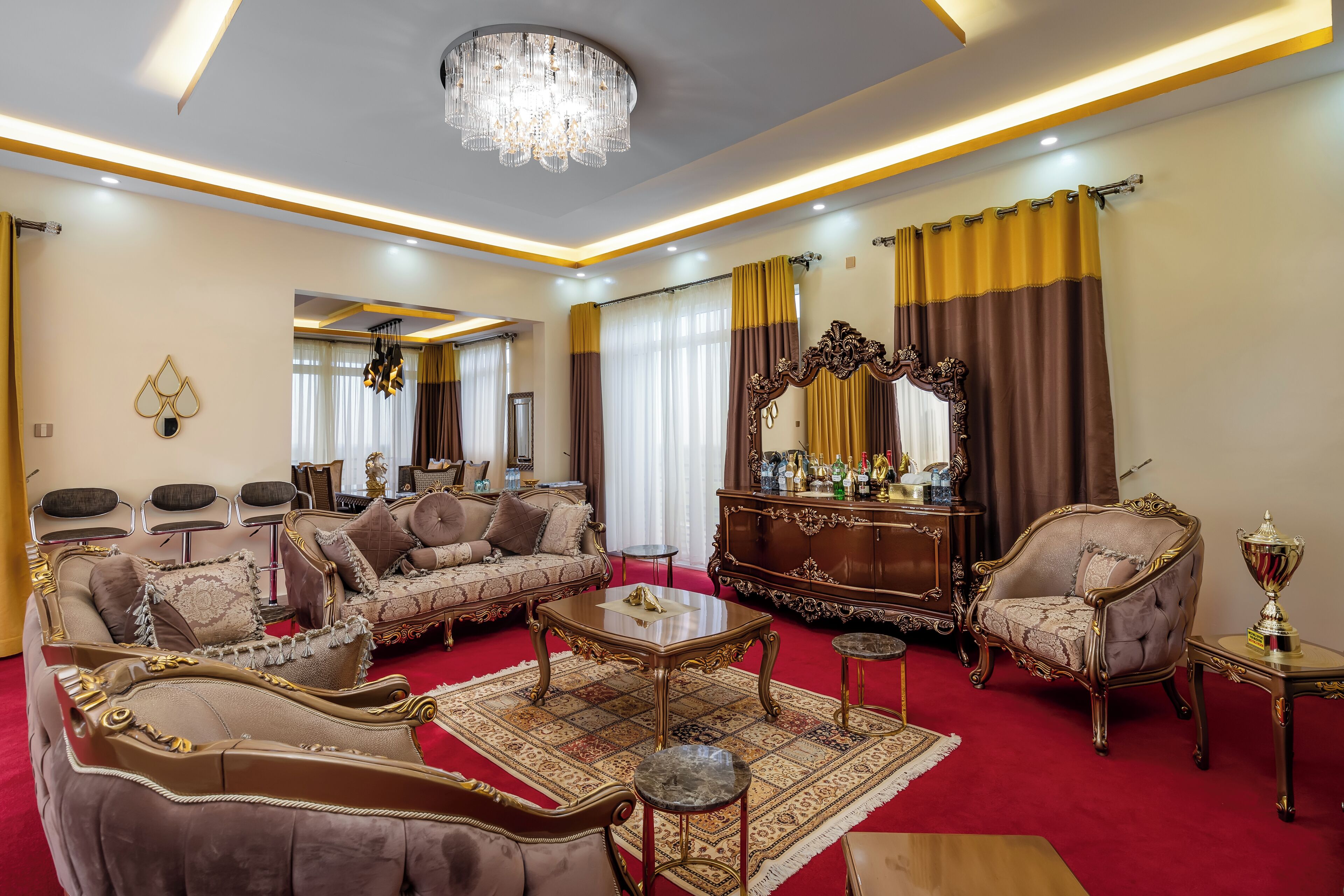 A luxurious living room with a red carpet, ornate furniture, and a chandelier.