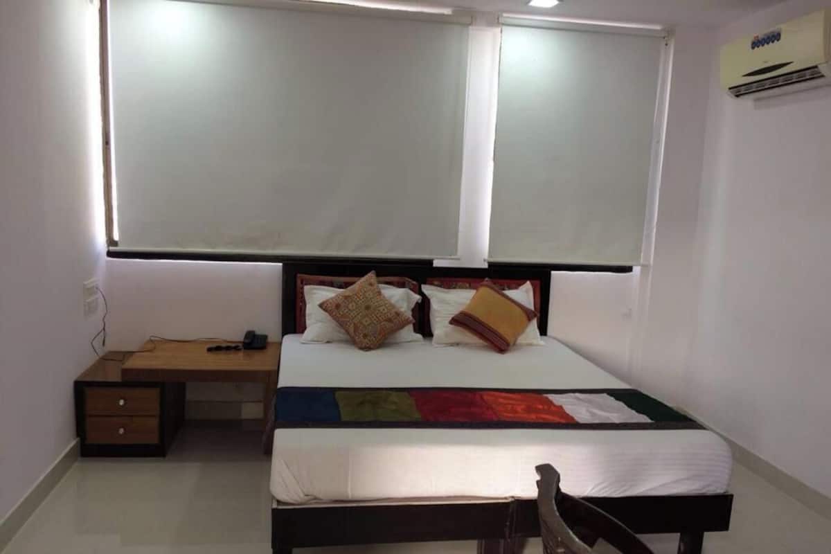 Un dormitorio con cama, mesitas de noche, escritorio y silla.