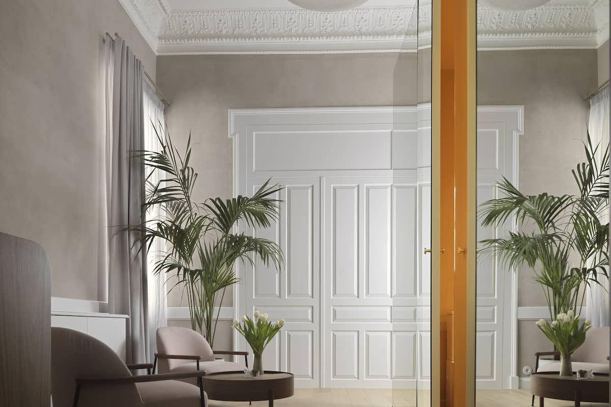 Uma sala de estar espaçosa com design moderno, que apresenta um amplo piso de madeira, um sofá confortável, uma mesa de centro e duas plantas em vasos.