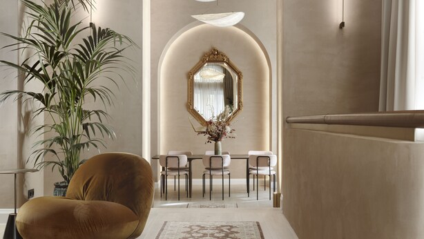 Um interior moderno com uma poltrona confortável, uma área de jantar com cadeiras, um espelho grande e um lustre.