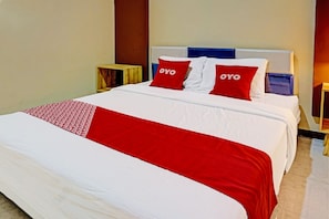 A hotel room with a large bed, two bedside tables, and a red and white bedspread. - Ngajeng Peken Home Stay (Batu)