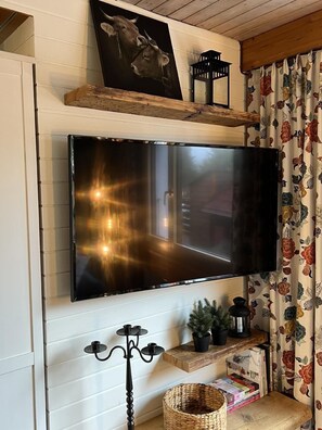 Cozy living space with a large flat-screen TV, candelabra, and a potted plant.
