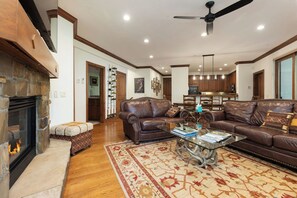 A spacious living room with a fireplace, leather sofas, a coffee table, and a dining area in the background.
