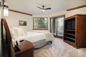 Ein Schlafzimmer mit einem Bett, einem Fernseher, einem Fenster und einer Tür, die nach draußen führt.