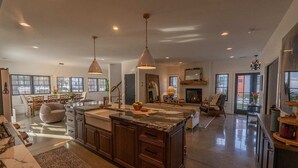 A spacious kitchen with a large island, pendant lighting, and a fireplace. - Luxury Douglas Beach House (Douglas)