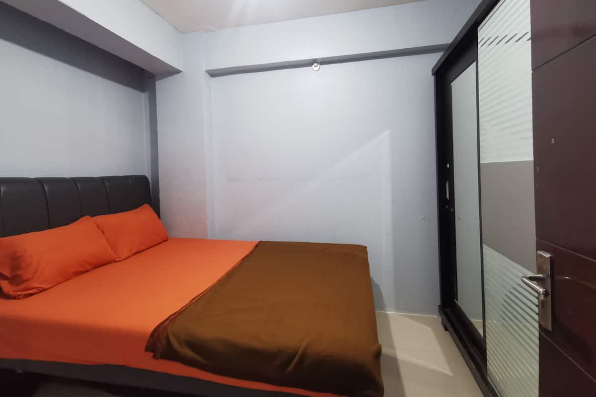 A bedroom with a bed, a wardrobe, and a door.