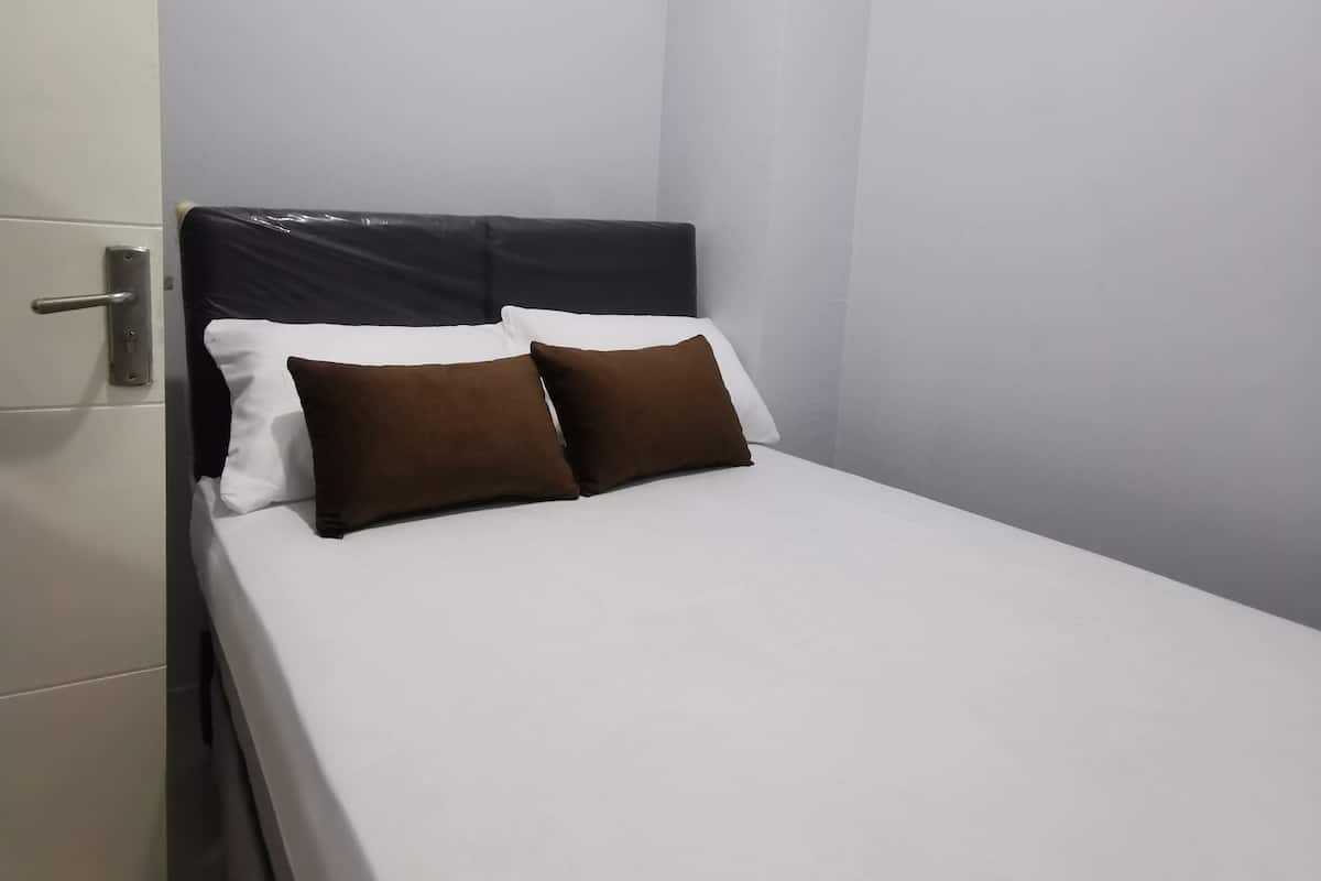 A single bed with a headboard, white bedding, and two brown pillows.