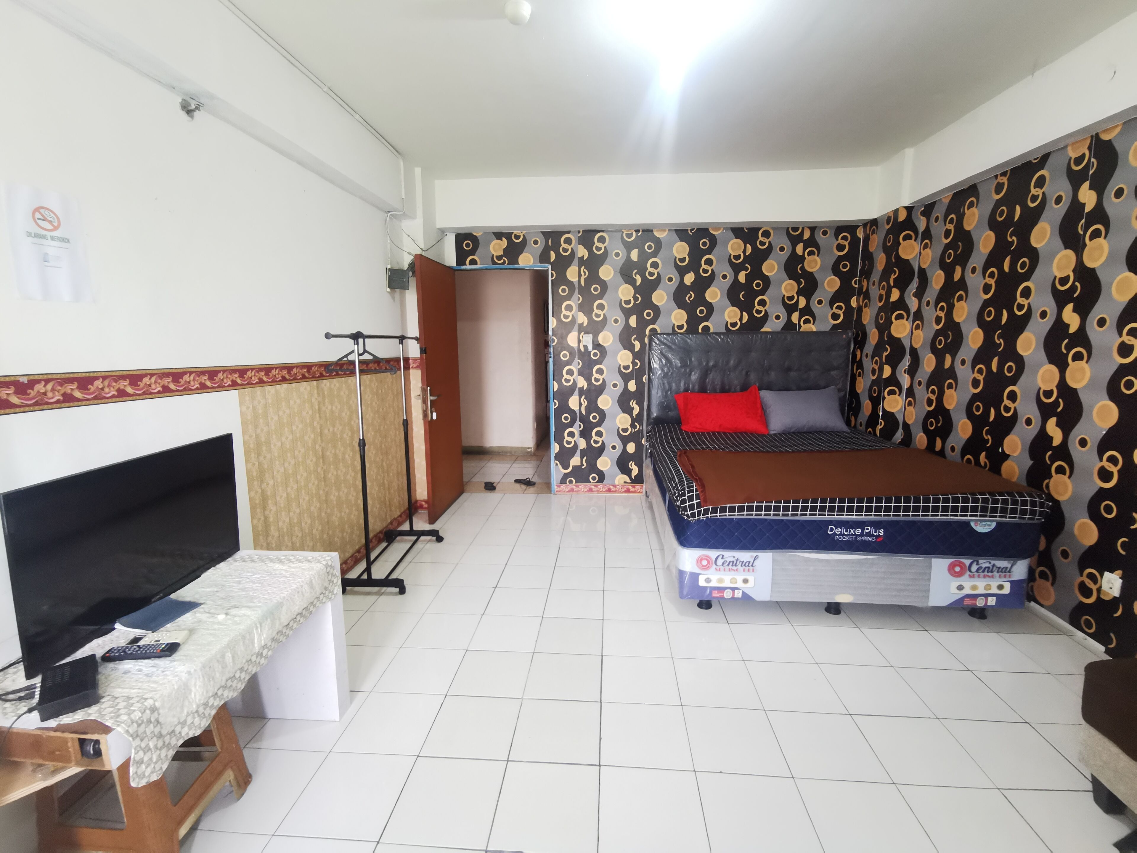 A bedroom with a bed, a desk with a computer, and a TV.