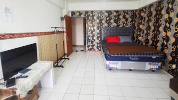 A bedroom with a bed, a desk with a computer, and a TV.