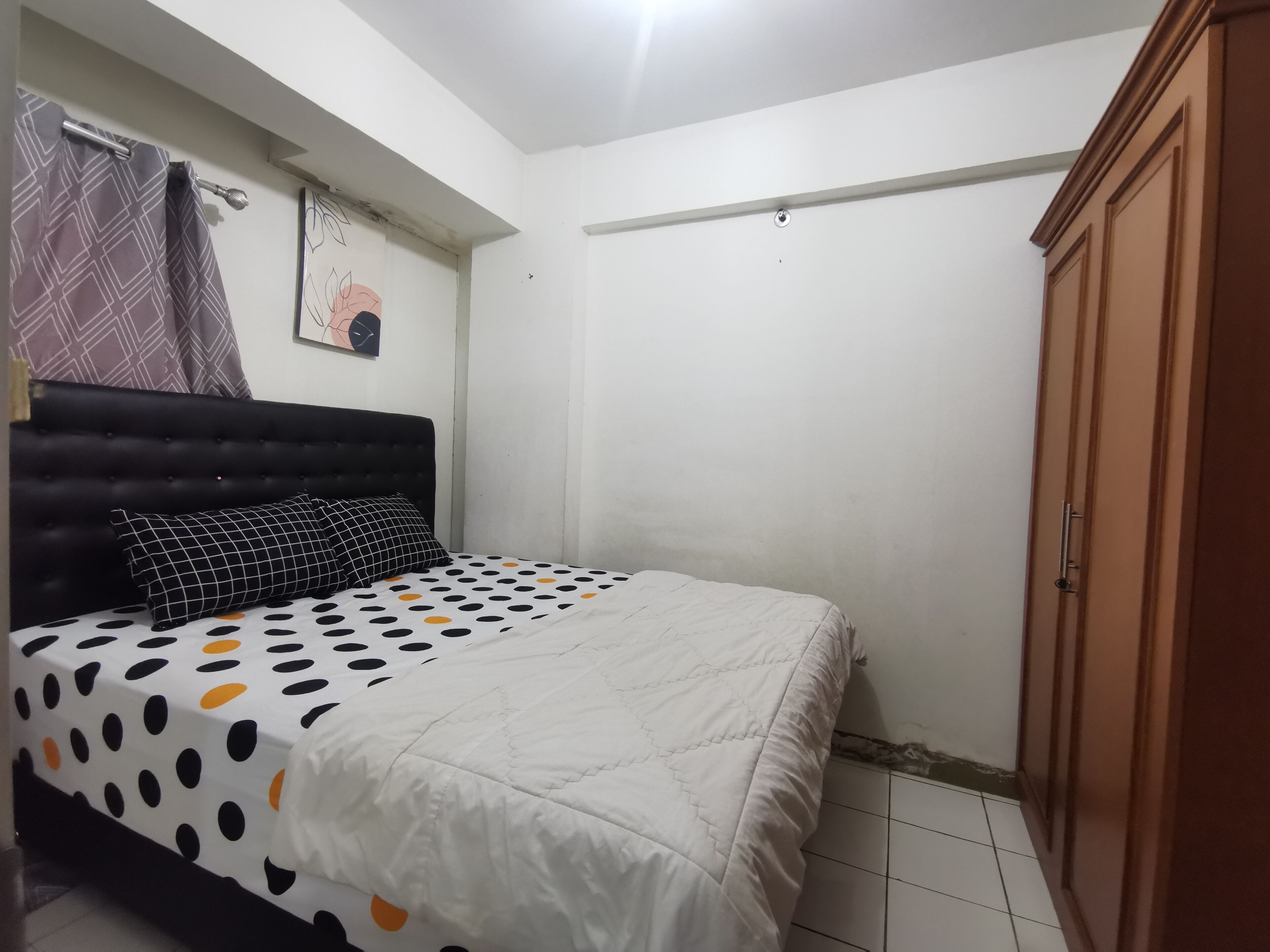 A bedroom with a bed, a wardrobe, a wall clock, and a curtain.