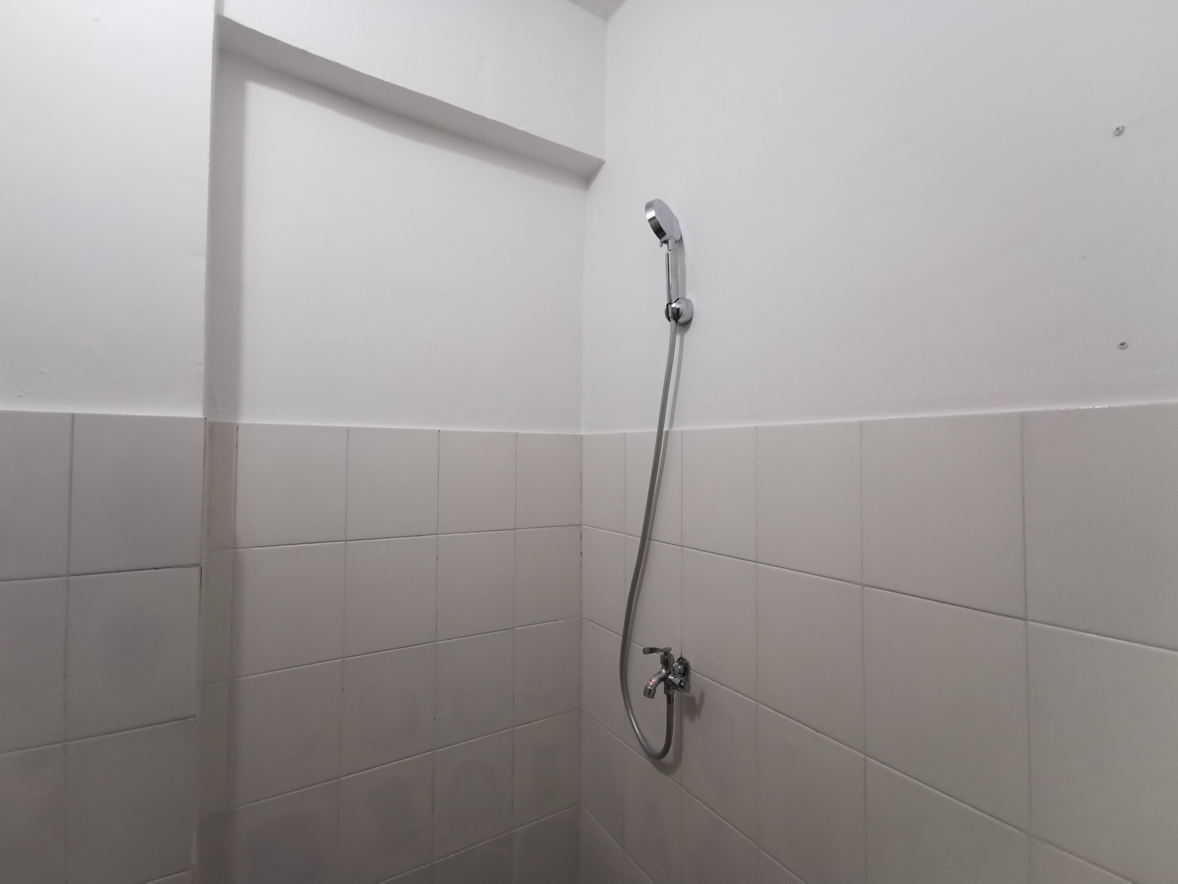A shower with a handheld showerhead and a wall-mounted faucet.