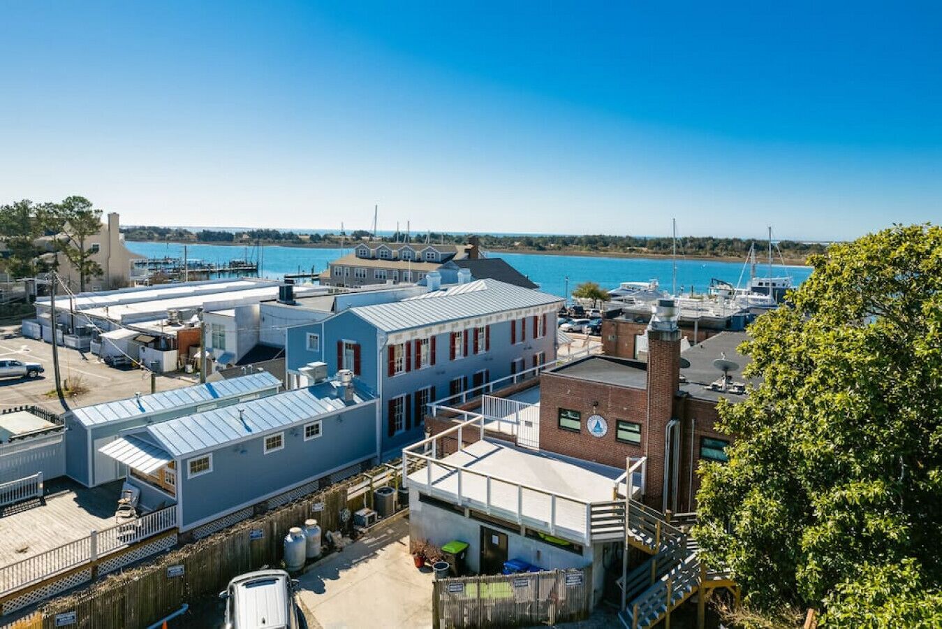 A coastal industrial area with buildings, a dock, and a clear blue sky.