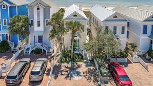 A coastal hotel with multiple-story buildings, a paved driveway, parked cars, and a view of the ocean. - Welcome to Stella Di Mare! (St. George Island)