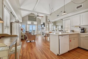 A spacious kitchen with a large island, wooden flooring, and white cabinetry.