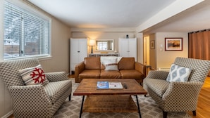 A living room with a brown leather sofa, patterned armchairs, a wooden coffee table, and a large window with blinds. - Close to Main Street, Access to Nearby Ski Resorts; Private Patio! (Frisco)