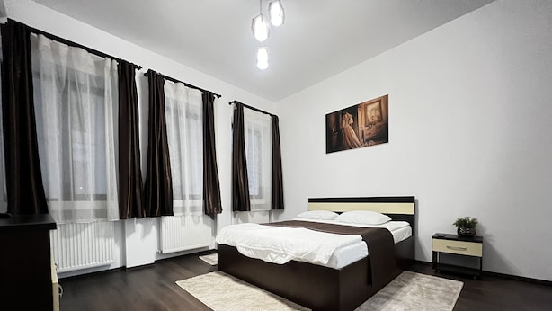 A modern bedroom with a large bed, a bedside table, a nightstand, and a painting on the wall. - Old City Appartment (București)
