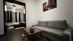 A modern living room with a grey sofa, a wooden coffee table, and a painting on the wall. - Old City Appartment (București)