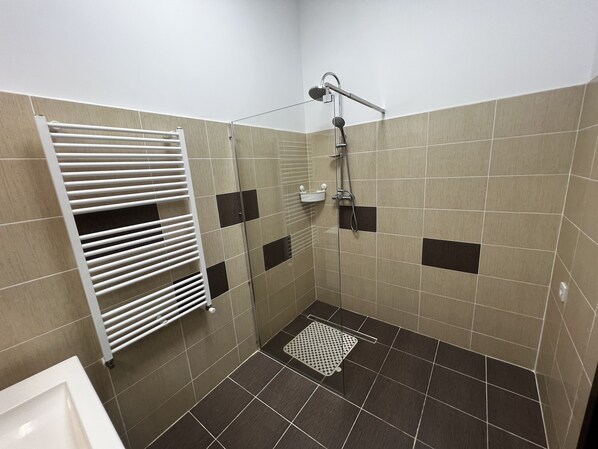 A small, tiled shower area with a white towel rack and a handheld showerhead. - Old City Appartment (București)